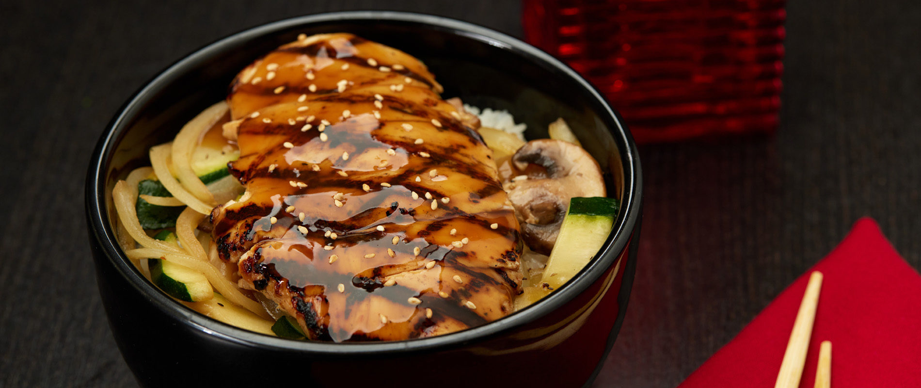 A bowl with grilled chicken in on a bed of rice.